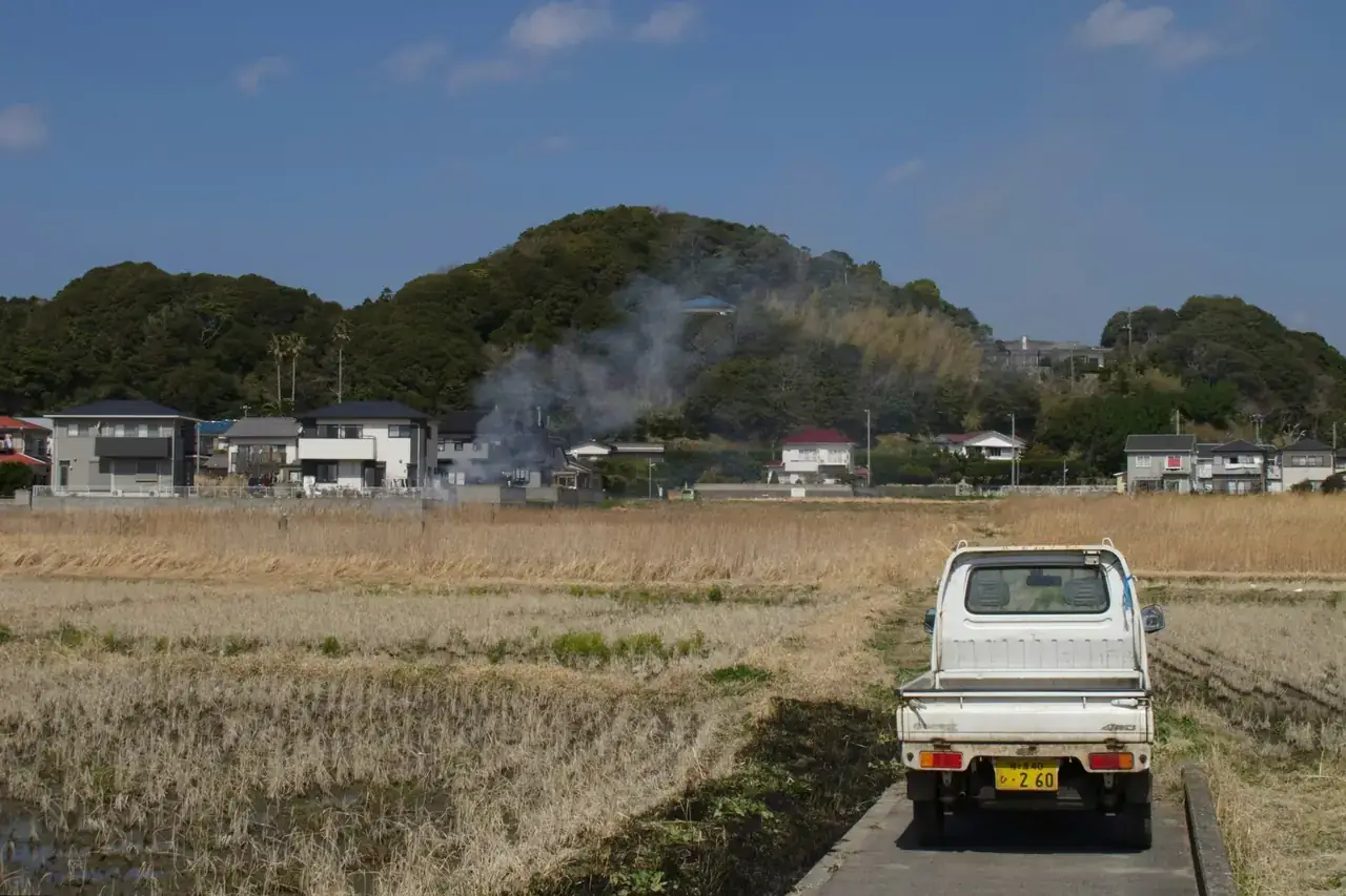 White 4WD Kei truck on a farm road beside rice fields in Japan