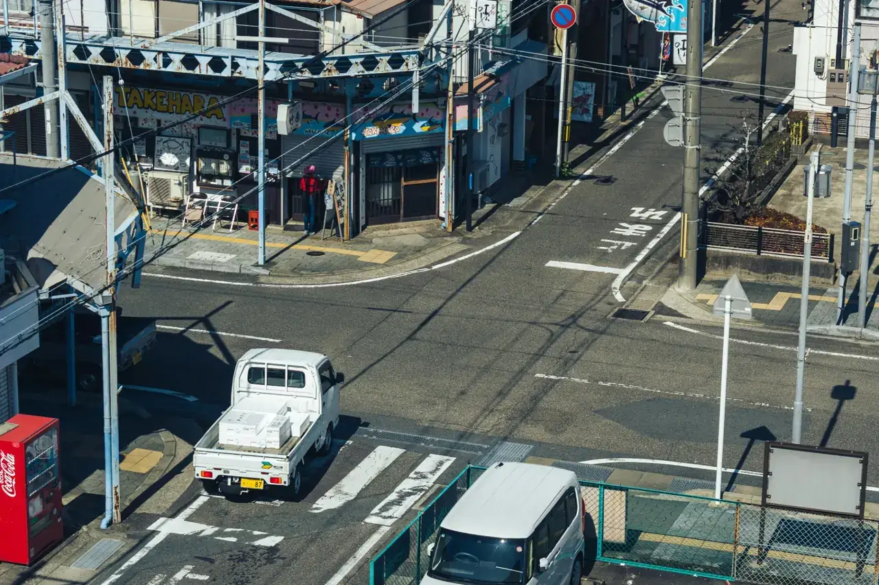 White Japanese Kei truck parked on a street corner in Japan with cargo in the bed